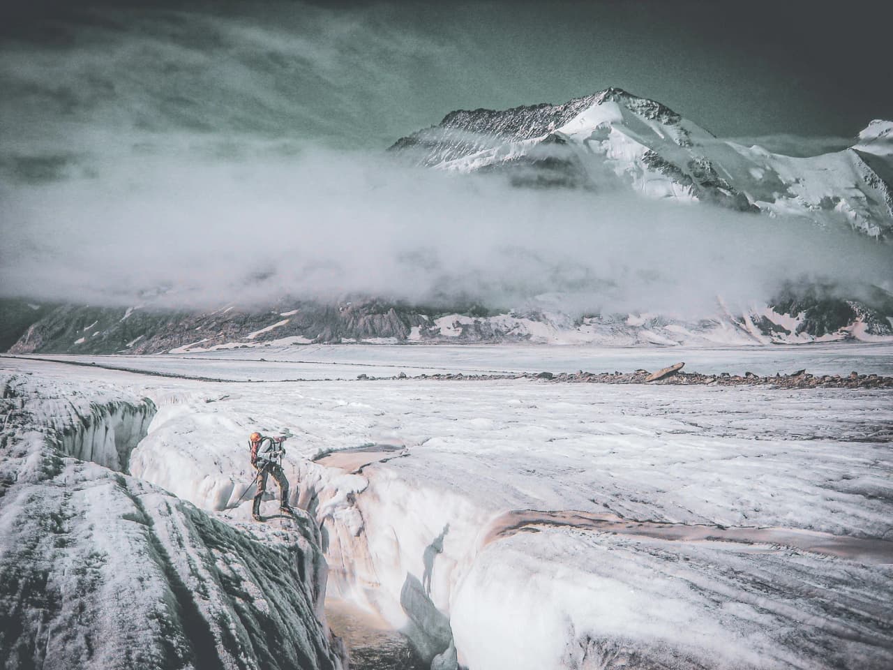 A man hiking on the Aletsch glacier, surrounded by majestic peaks and mist.