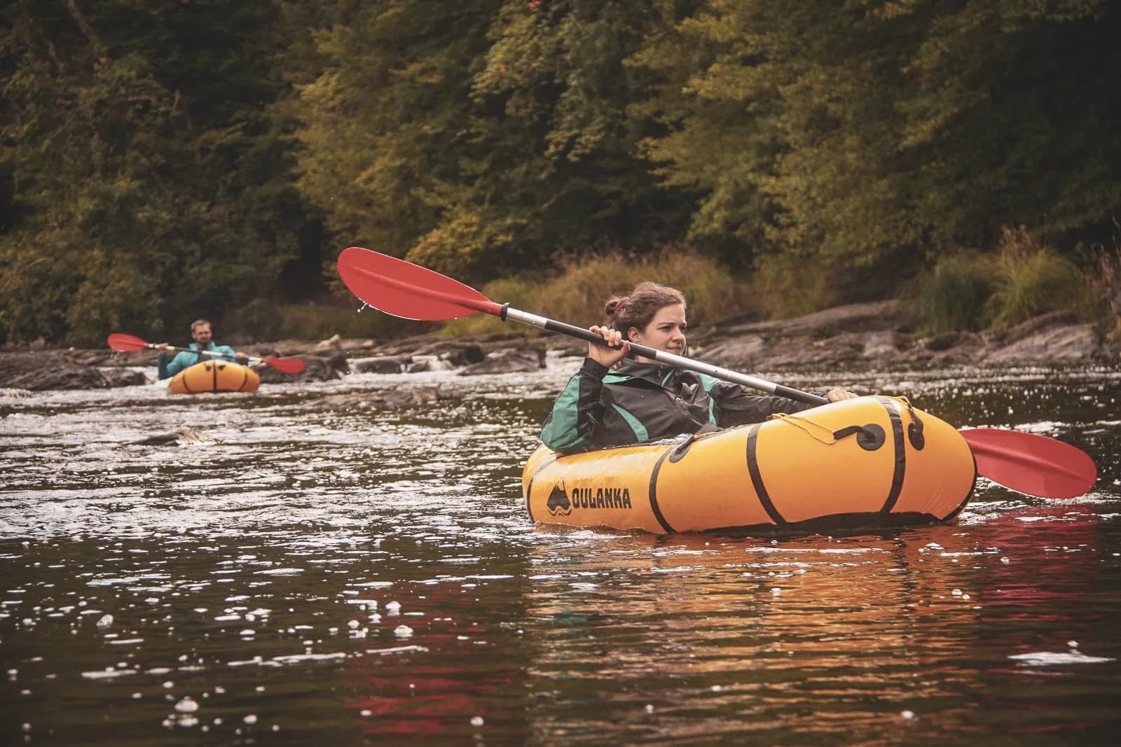 Twee mensen peddelden rustig in een packraft op de prachtige Semois, omgeven door groen.