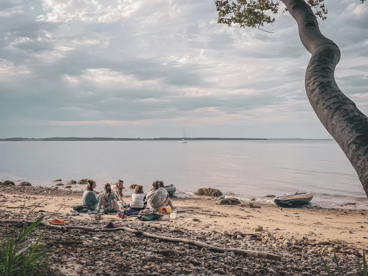 Un groupe de personnes se détend sur une plage paisible, face à un paysage marin serein.