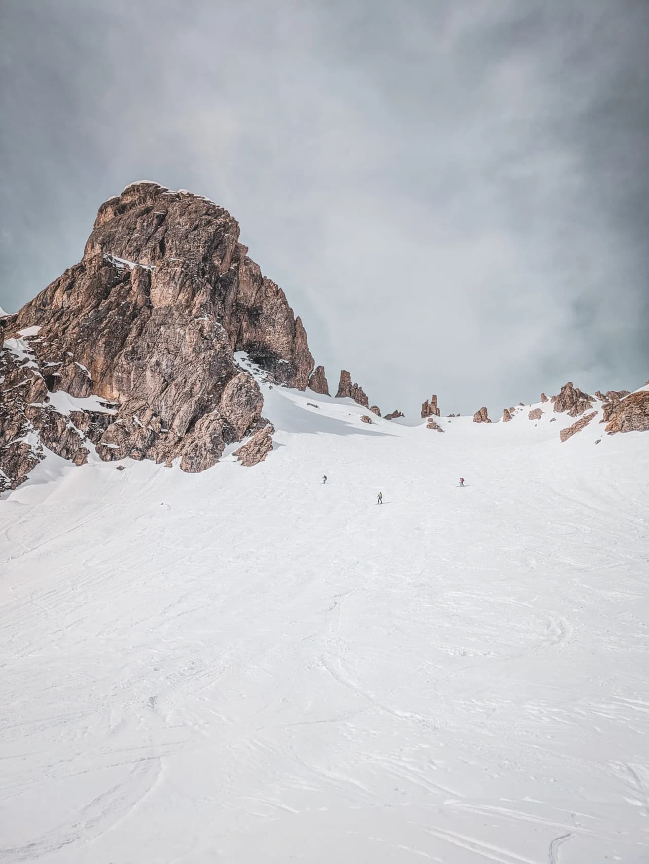 Vast snow-covered slopes beneath rocky peaks, ideal for ski touring.