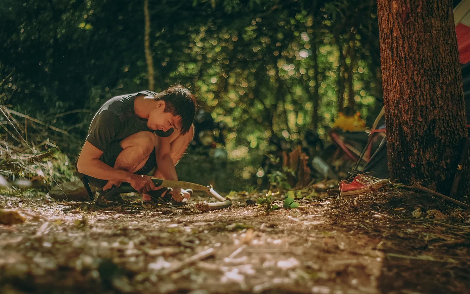 A young man in the wilderness, learning about survival in a green and wild setting.