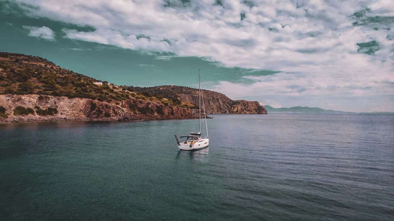 Voilier paisible dans les eaux calmes entourées de collines verdoyantes, invitation à l'évasion.
