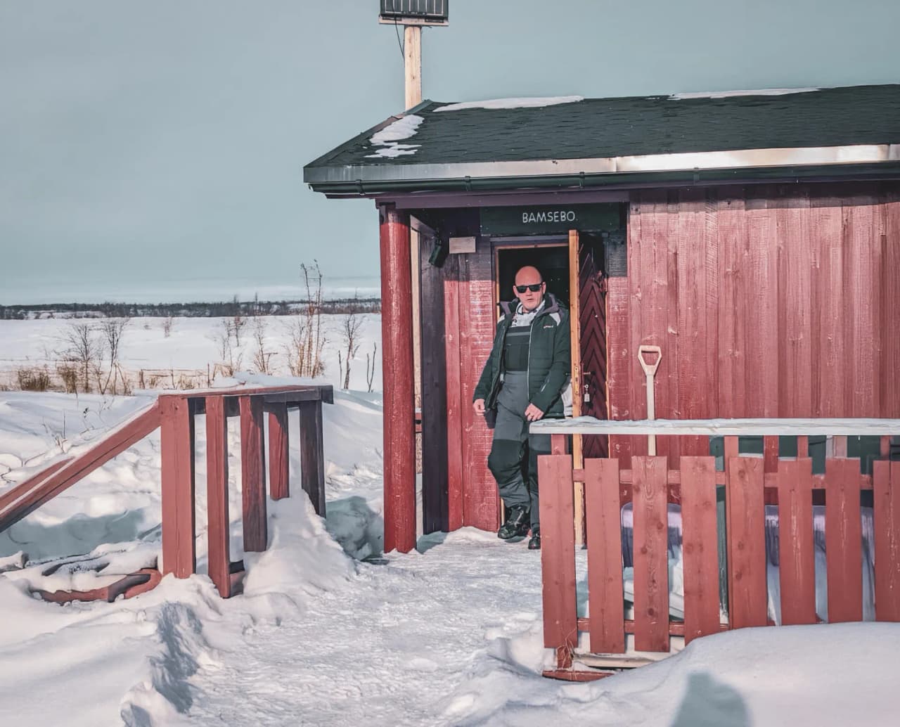 Man in the sun in front of a snow-covered Mountain hut, ready for an adventure in Norwegian Lapland.