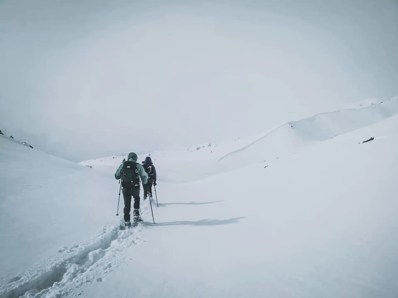 Two hikers make their way along a snow-covered path, discovering enchanting Alpine landscapes.