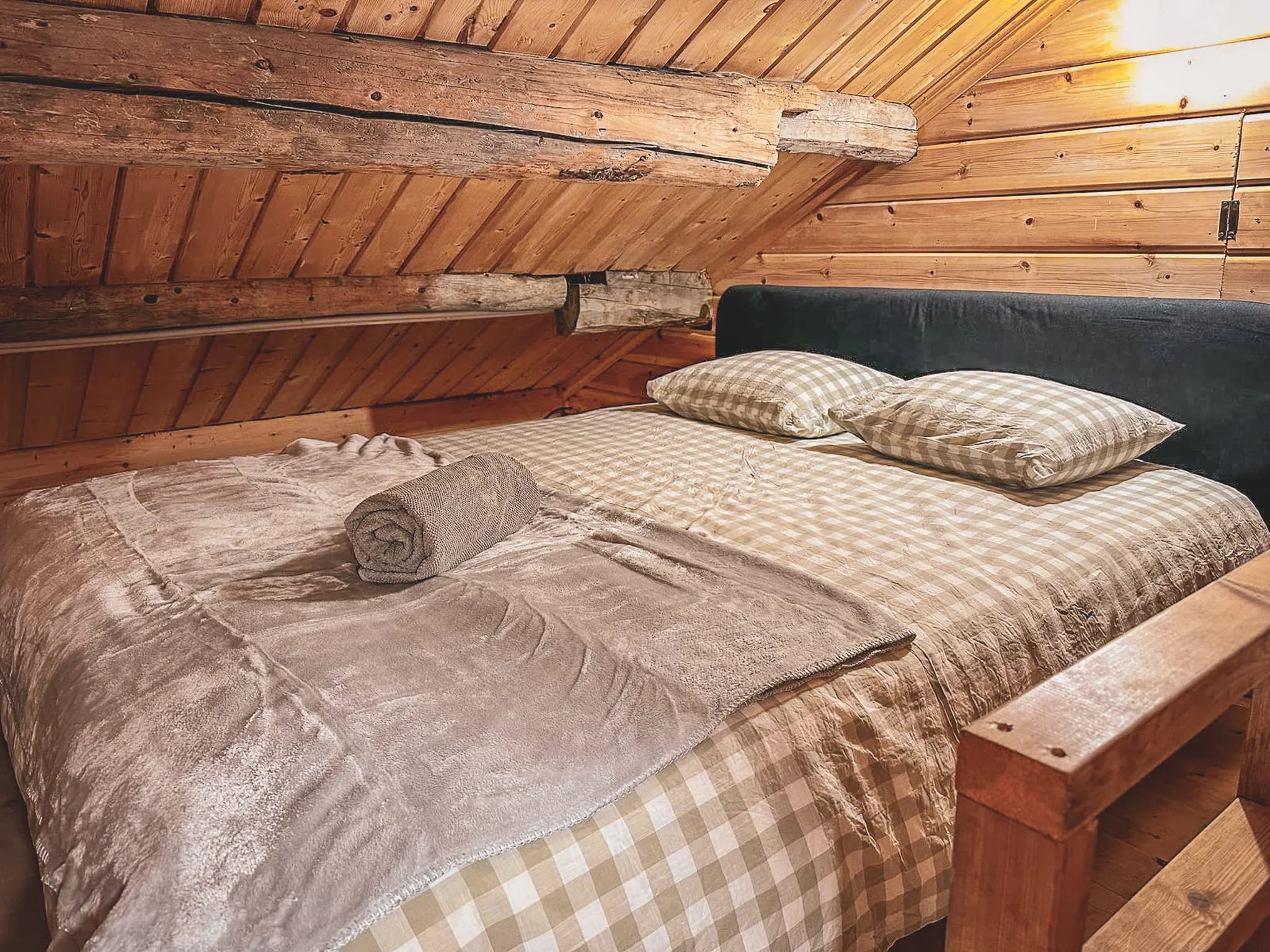 Warme houten slaapkamer, knus bed met plaids, cocooning sfeer in Zweeds Lapland.