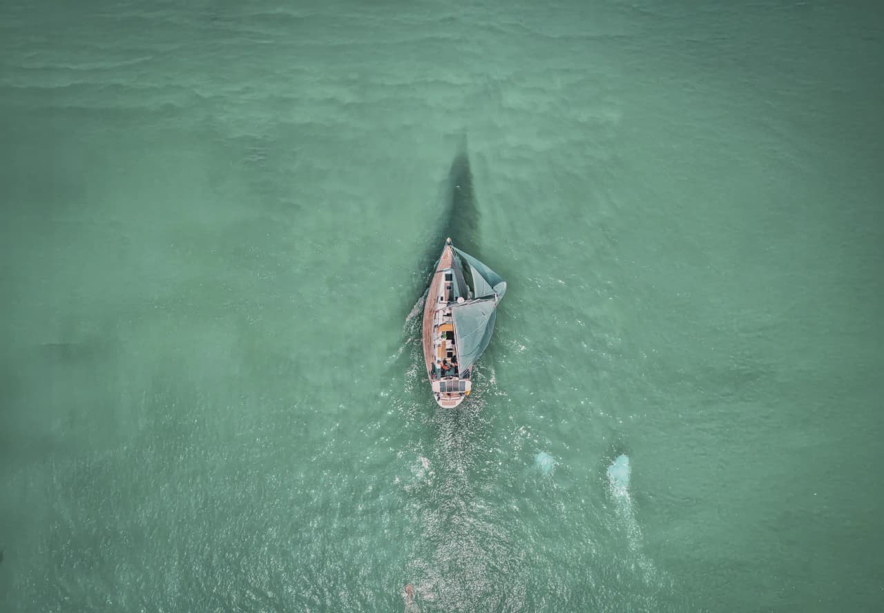 Un voilier glisse sur des eaux turquoises, invitant à l'évasion en Bretagne.