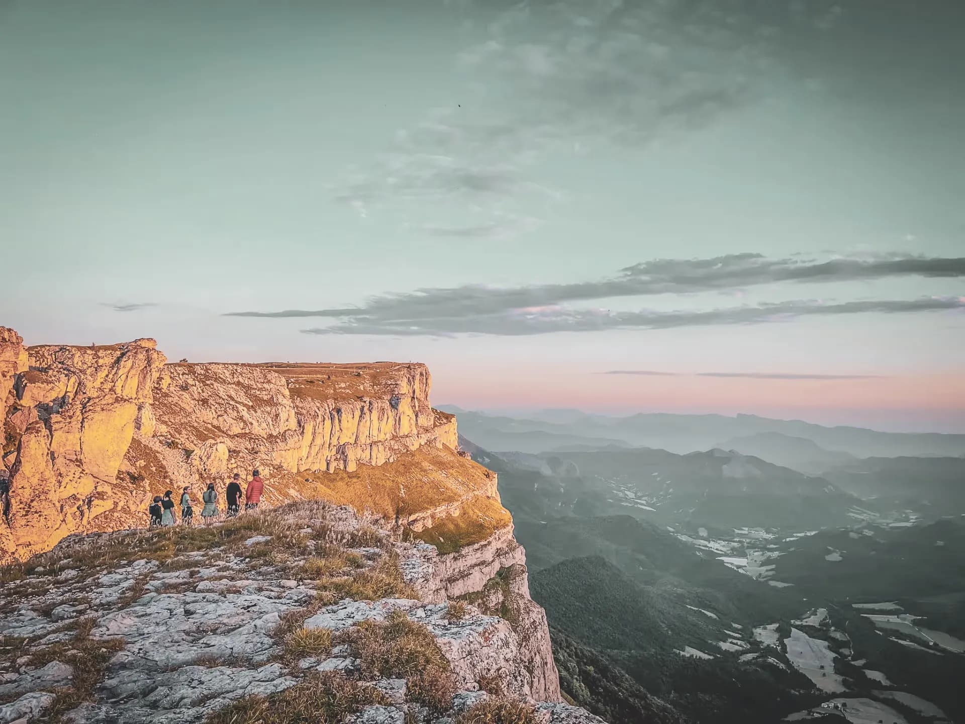 A group of hikers on a Vercors summit, facing a spectacular sunset.