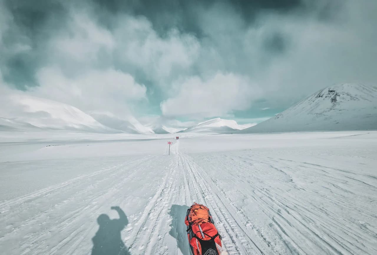 Nordic skiën in het besneeuwde landschap van Kungsleden, met majestueuze bergen en blauwe luchten.