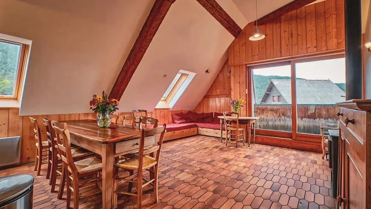 Espace chaleureux en bois avec vue panoramique sur les montagnes, idéal pour se détendre après un trail.