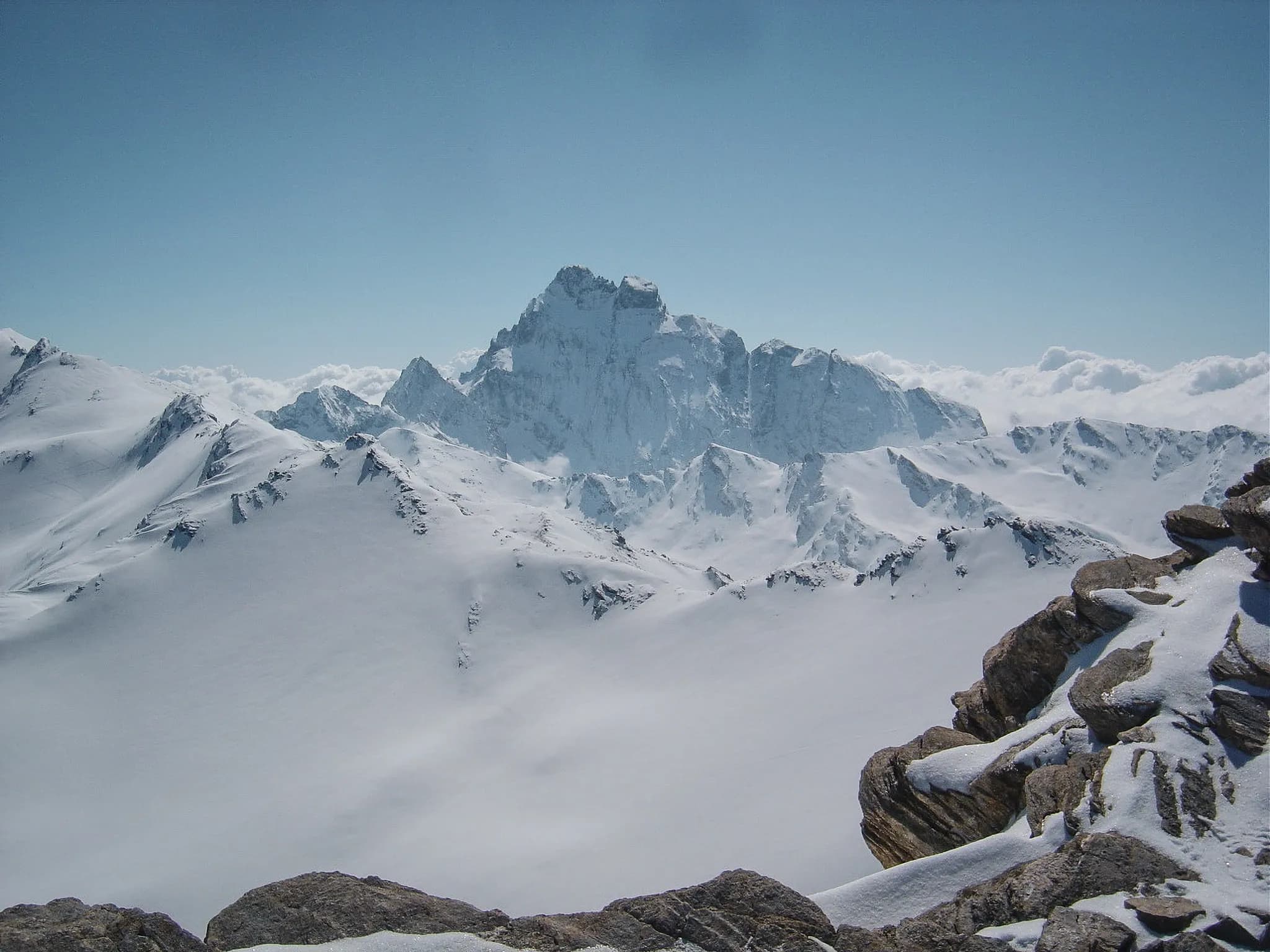 A majestic view of the snow-capped Queyras peaks under a brilliant blue sky.