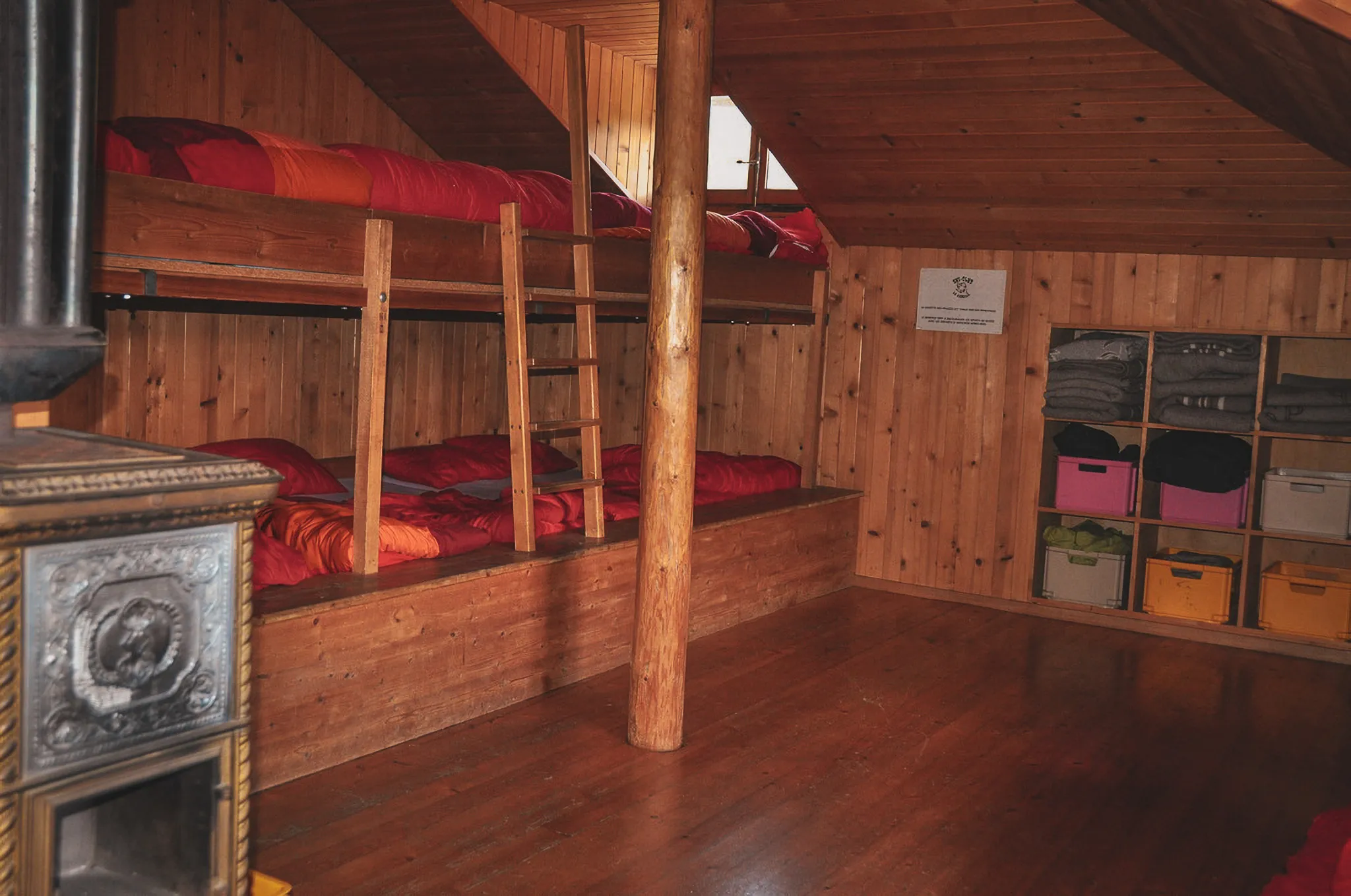 Warme houten kamer, stapelbedden met kleurrijke dekens, ideaal voor een winters uitje.