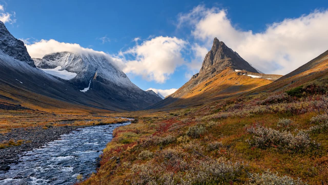 Vallée sauvage en Laponie suédoise, montagnes majestueuses, ruisseau et paysages colorés.