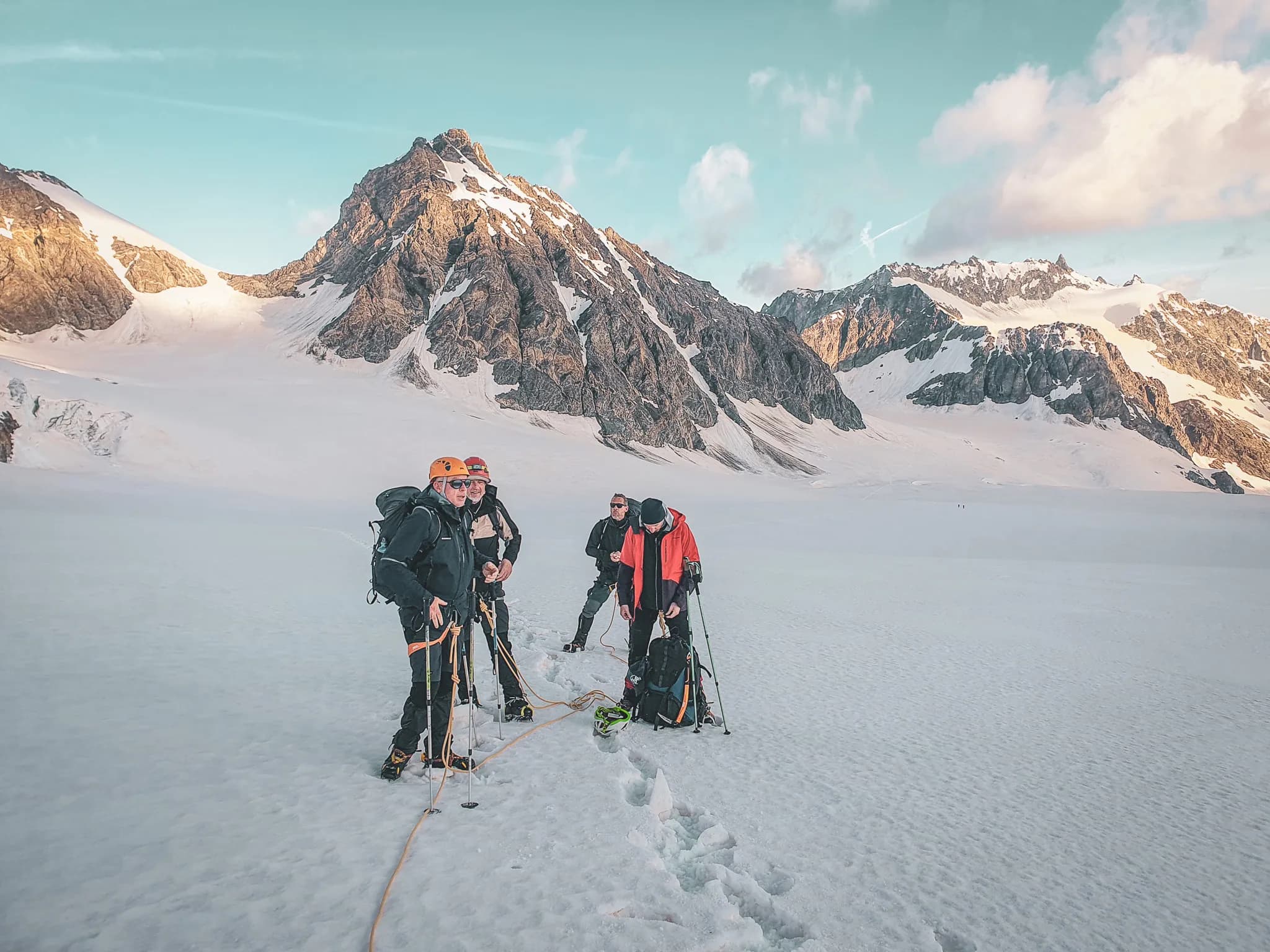 Mountaineers on a glacier, surrounded by majestic mountains at dusk. An unforgettable adventure!
