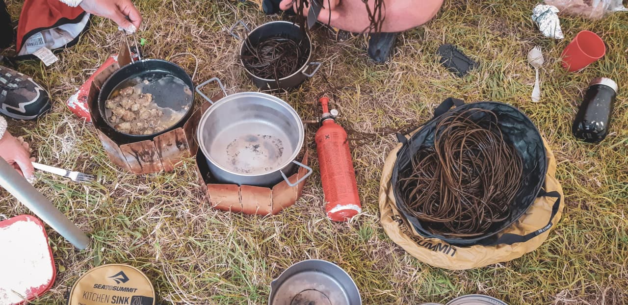 Preparing dishes in the open air, pots and ingredients in the midst of lush greenery.
