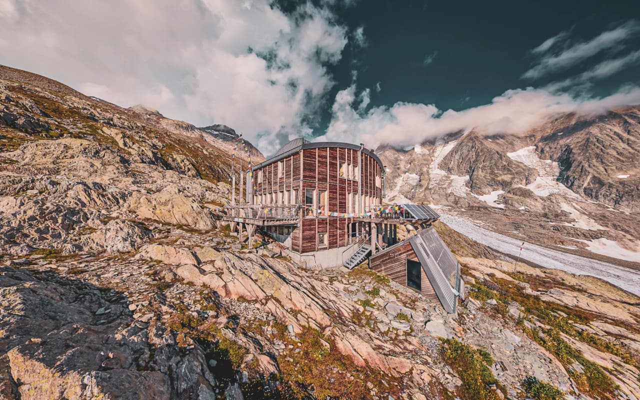 Een houten Berghut aan de voet van de Dômes de Miage, omgeven door bergen en gletsjers, een uitnodiging tot avontuur.