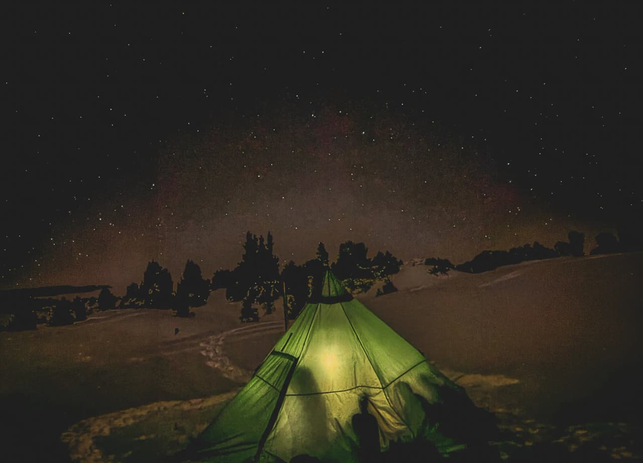 Bivouac sous un tipi illuminé, étoilé dans la Réserve du Vercors, paysage enchanteur.