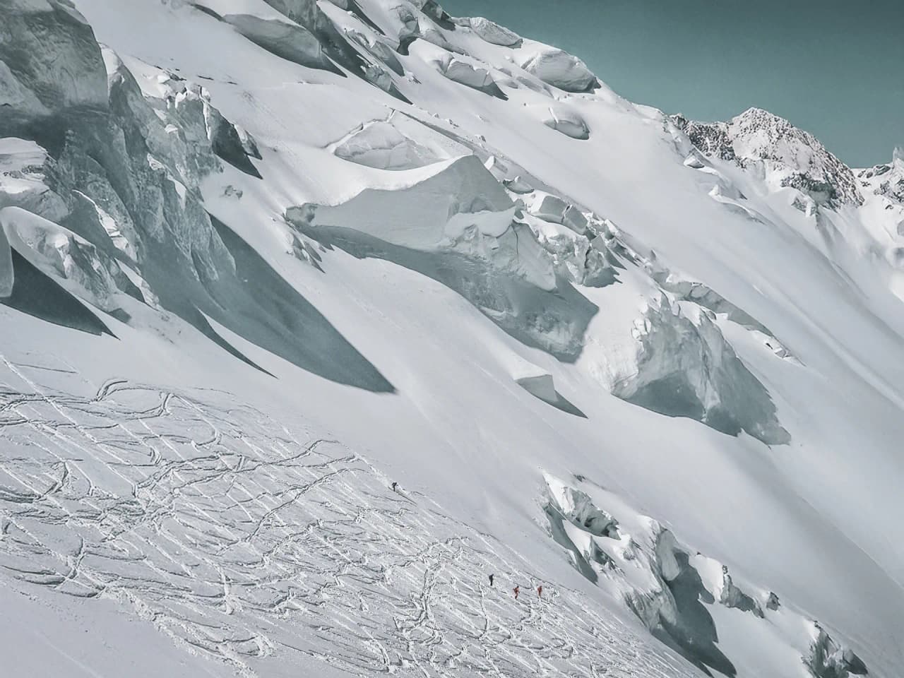 Montagnes enneigées du Mont Blanc, avec des traces de ski et des alpinistes en exploration.