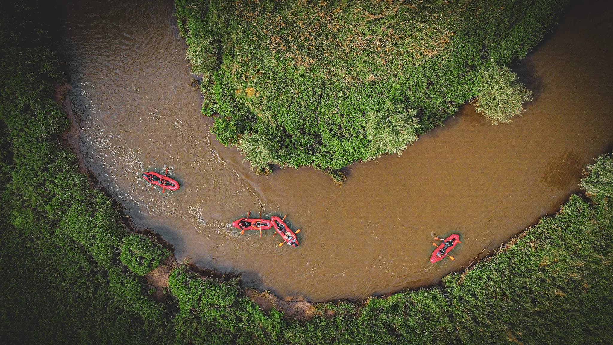 Expédition en packraft sur une rivière sinueuse, entourée de verdure luxuriante.