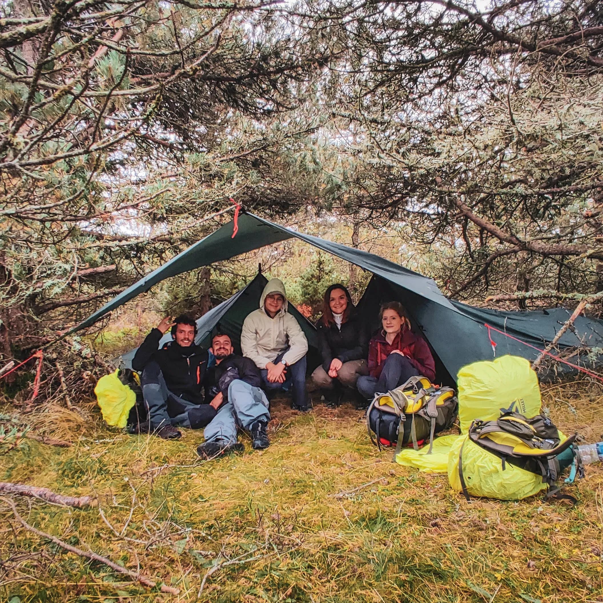 Een groep deelnemers onder een natuurlijke beschutting in de Vercors, klaar voor een bushcraftavontuur.