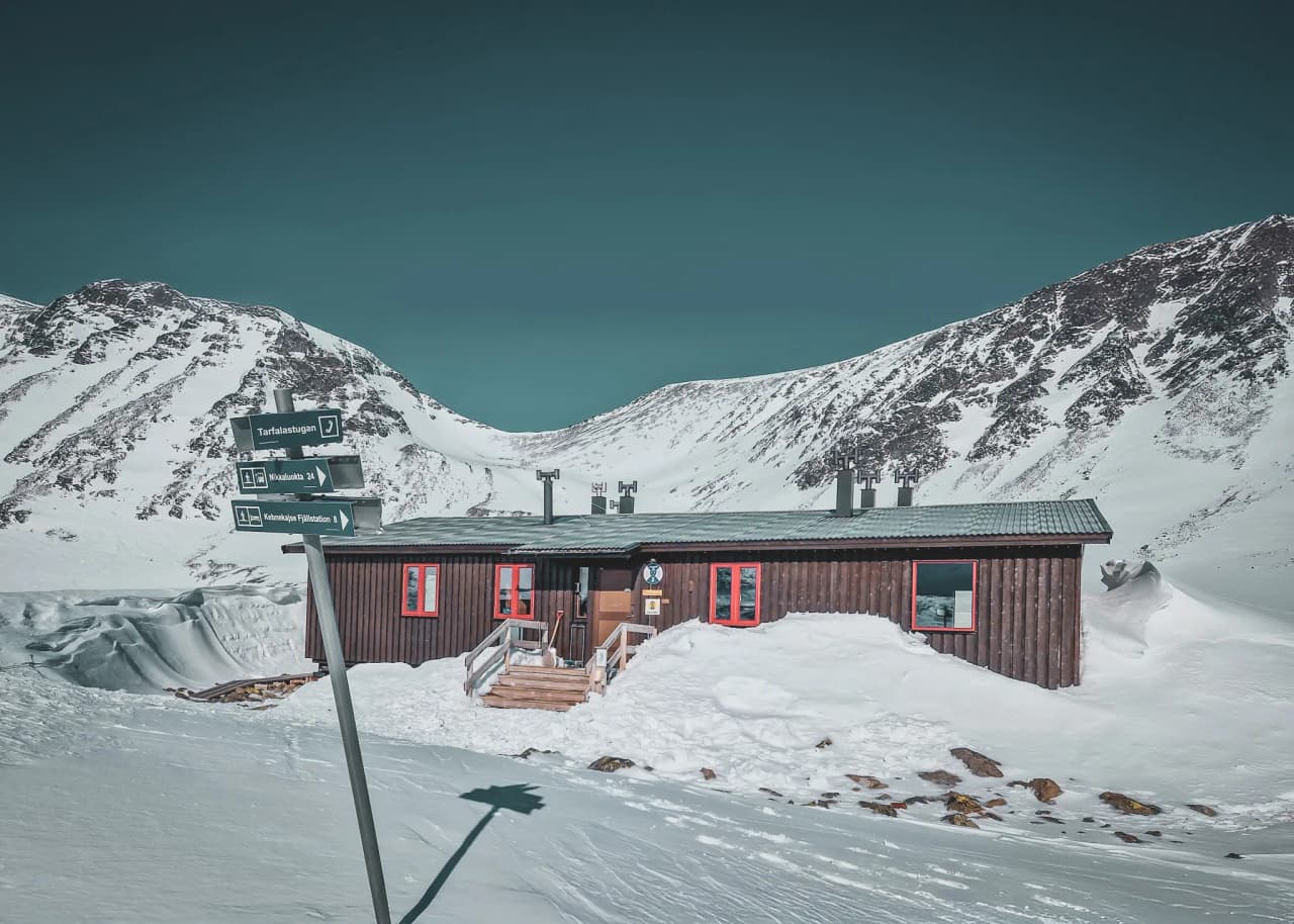 Berghut in een besneeuwd landschap, omringd door majestueuze bergen in Zweeds Lapland.