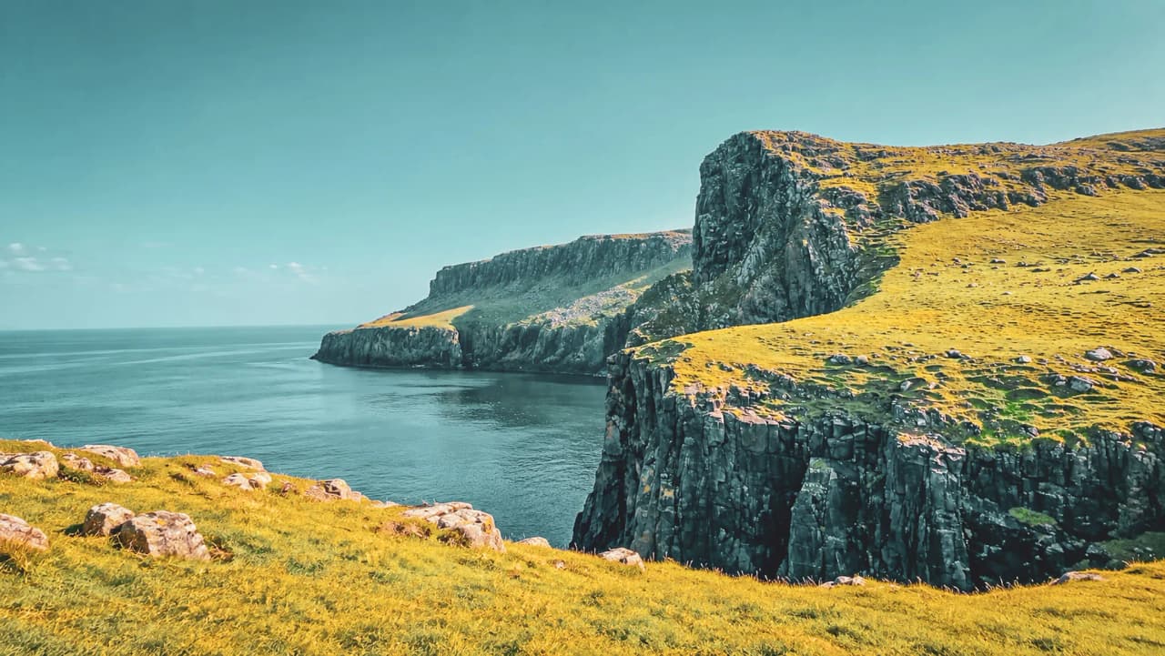 Adembenemend uitzicht op de groene kliffen van het eiland Skye, die uitkijken over een kalme zee.