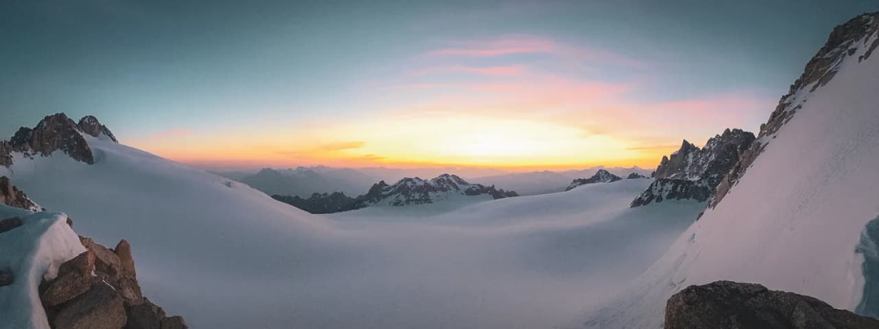 Een adembenemend panorama van besneeuwde toppen bij zonsopgang, een uitnodiging tot alpien avontuur.