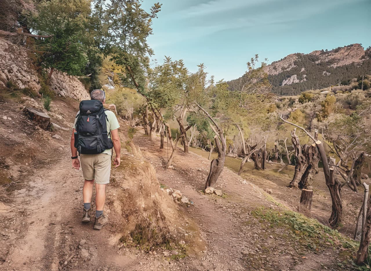 Un randonneur explore un sentier pittoresque de la Serra de Tramuntana, entouré de verdure.