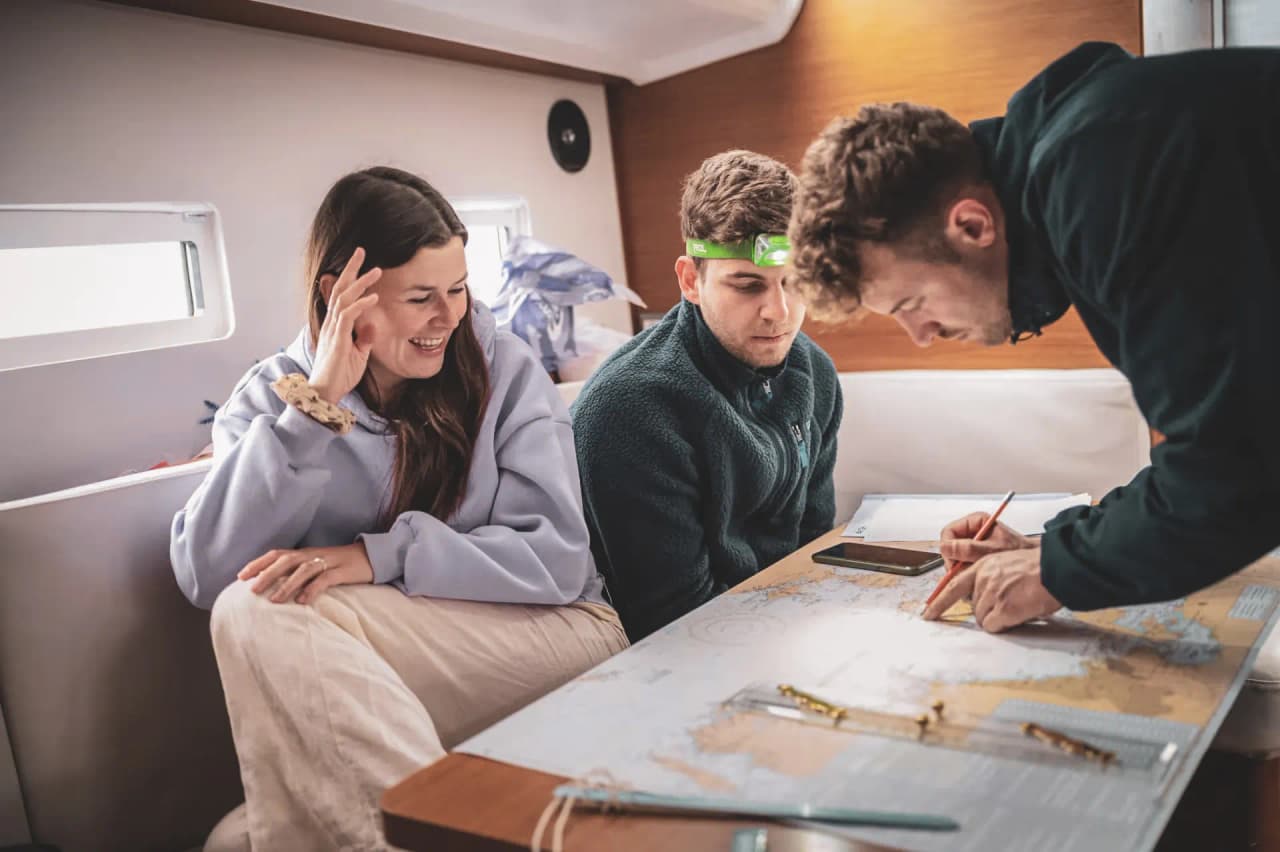 Trois jeunes naviguent sur un bateau, émerveillés par une carte des îles grecques.