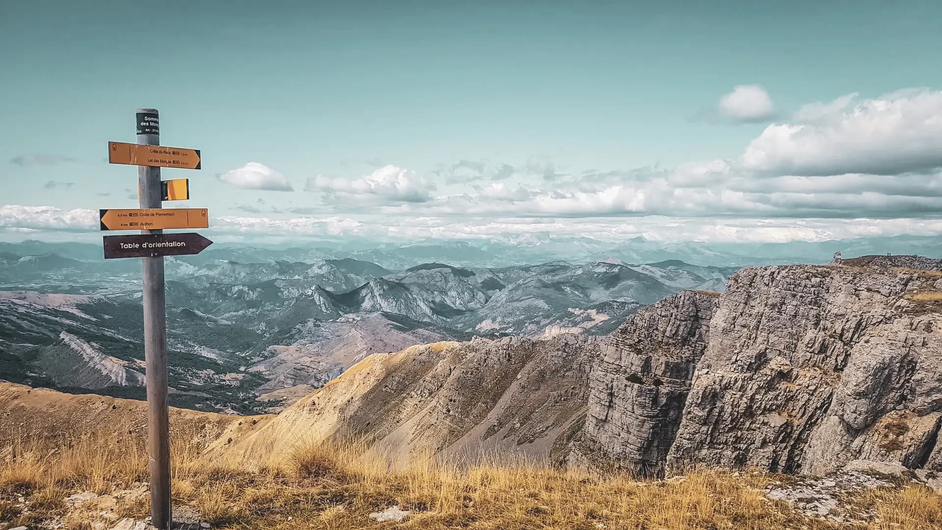 Panorama époustouflant des montagnes des Écrins avec un panneau indicateur de randonnée.