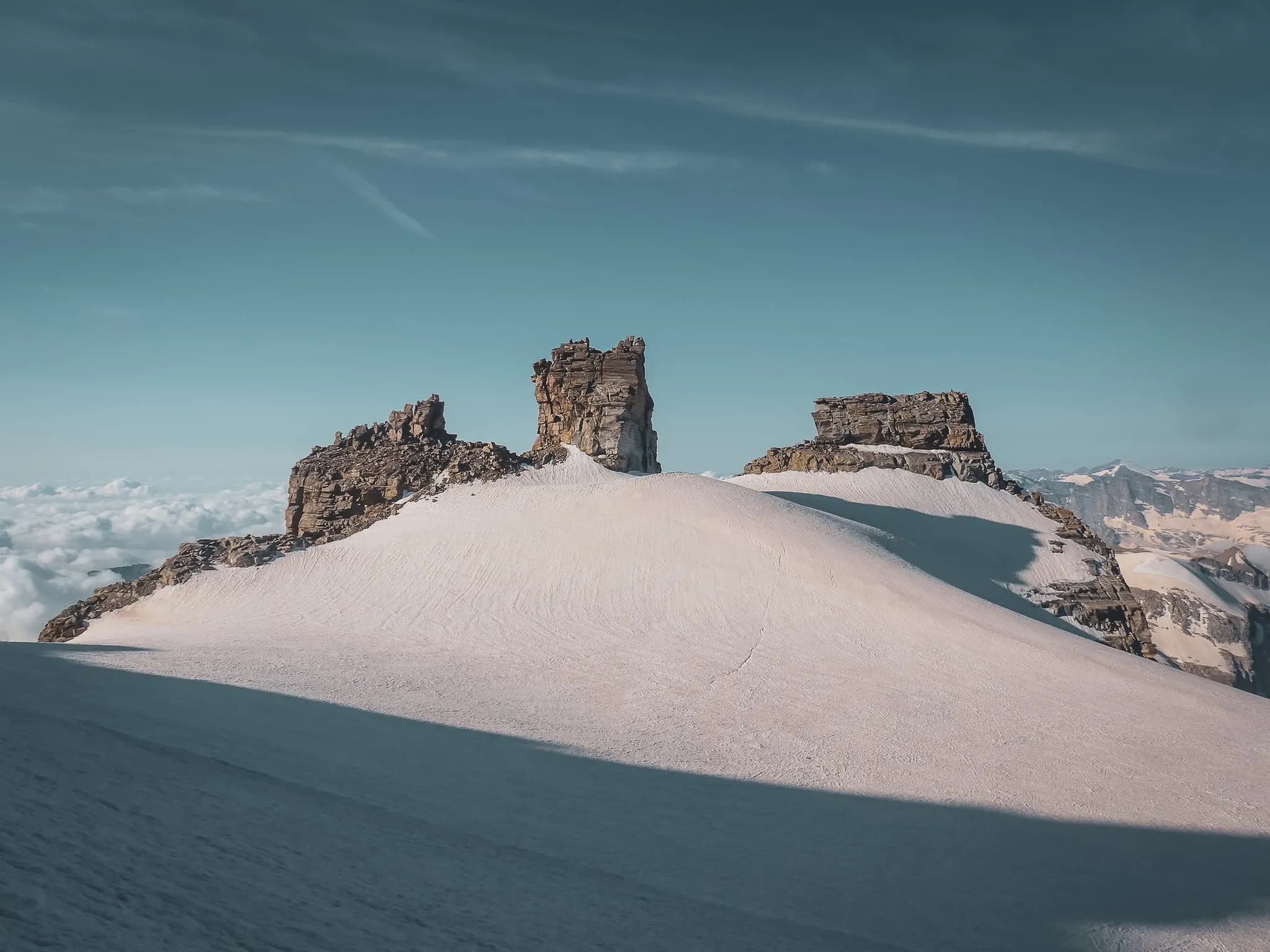 Gran Paradiso met zijn rotsige bergkam torent uit boven de gletsjer. De heldere lucht met blauwe tinten vormt een sterk contrast met de donkere rotsformaties.