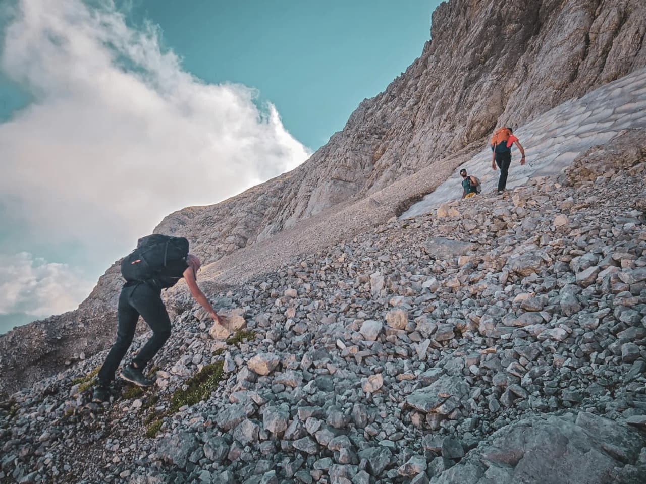 Hikers climbing rocky terrain in the magnificent Dolomites, under a blue sky.