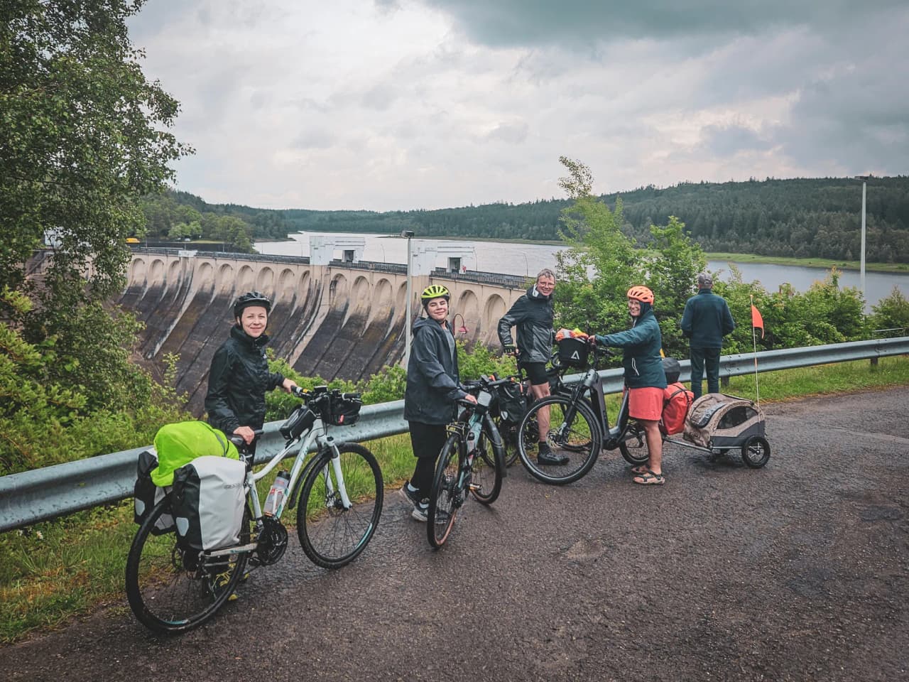 Groupe de cyclistes au bord d'un barrage, prêts pour une aventure dans les Hautes Fagnes.
