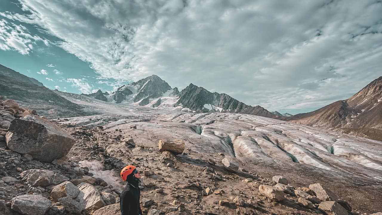 Un alpiniste contemplant un glacier majestueux sous un ciel nuageux à Chamonix.