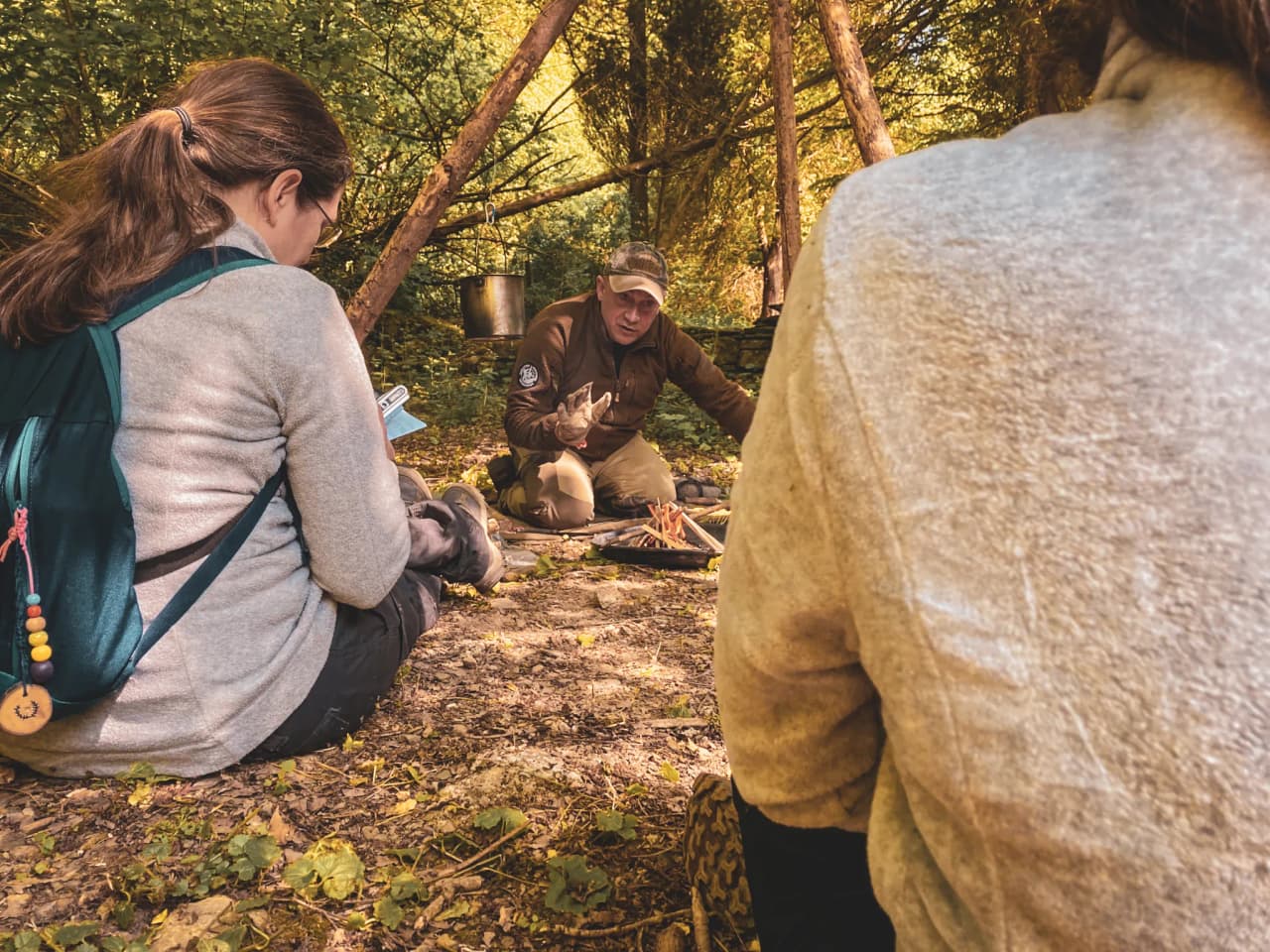 Un groupe apprend les techniques de survie en forêt, entouré de nature verdoyante.