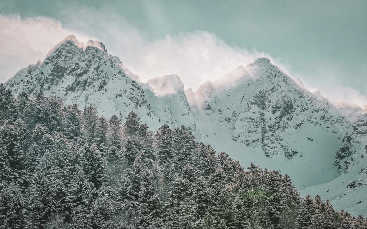 Snow-capped mountains under emerald skies, surrounded by lush green forests, an invitation to adventure.