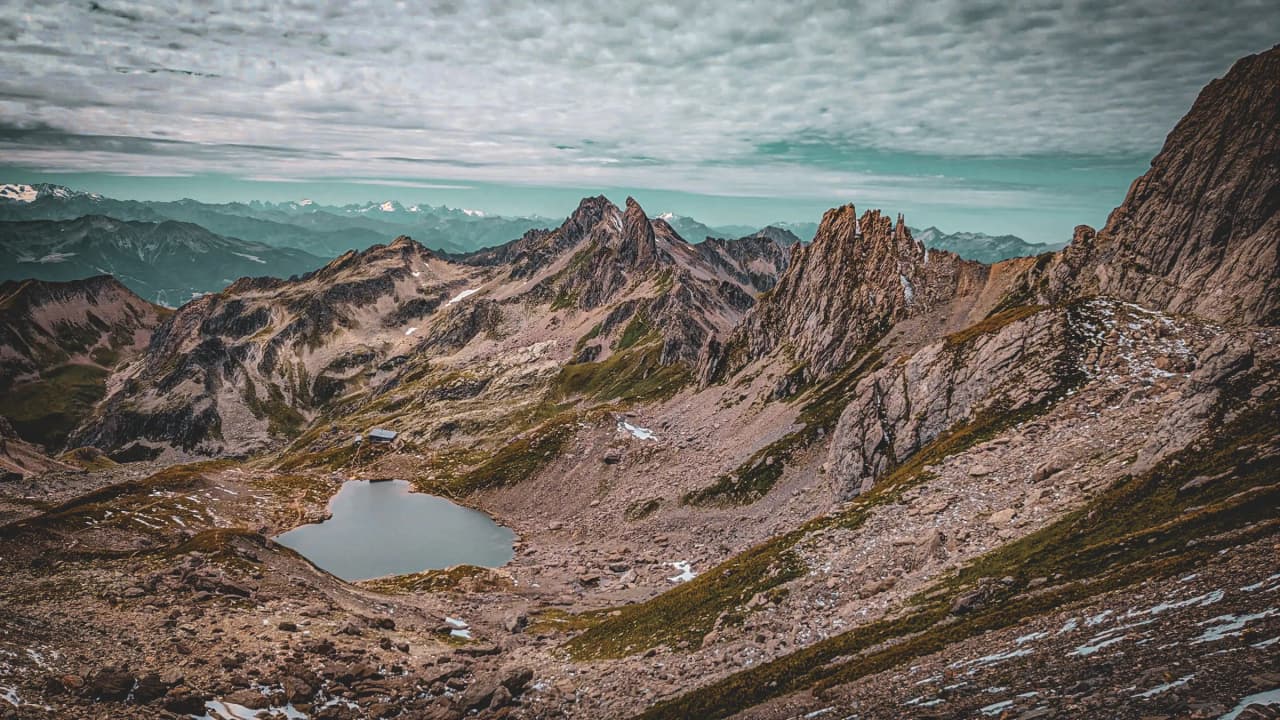 Panorama montagneux spectaculaire du Beaufortain, reflet dans un lac d'altitude, ciel dramatique.