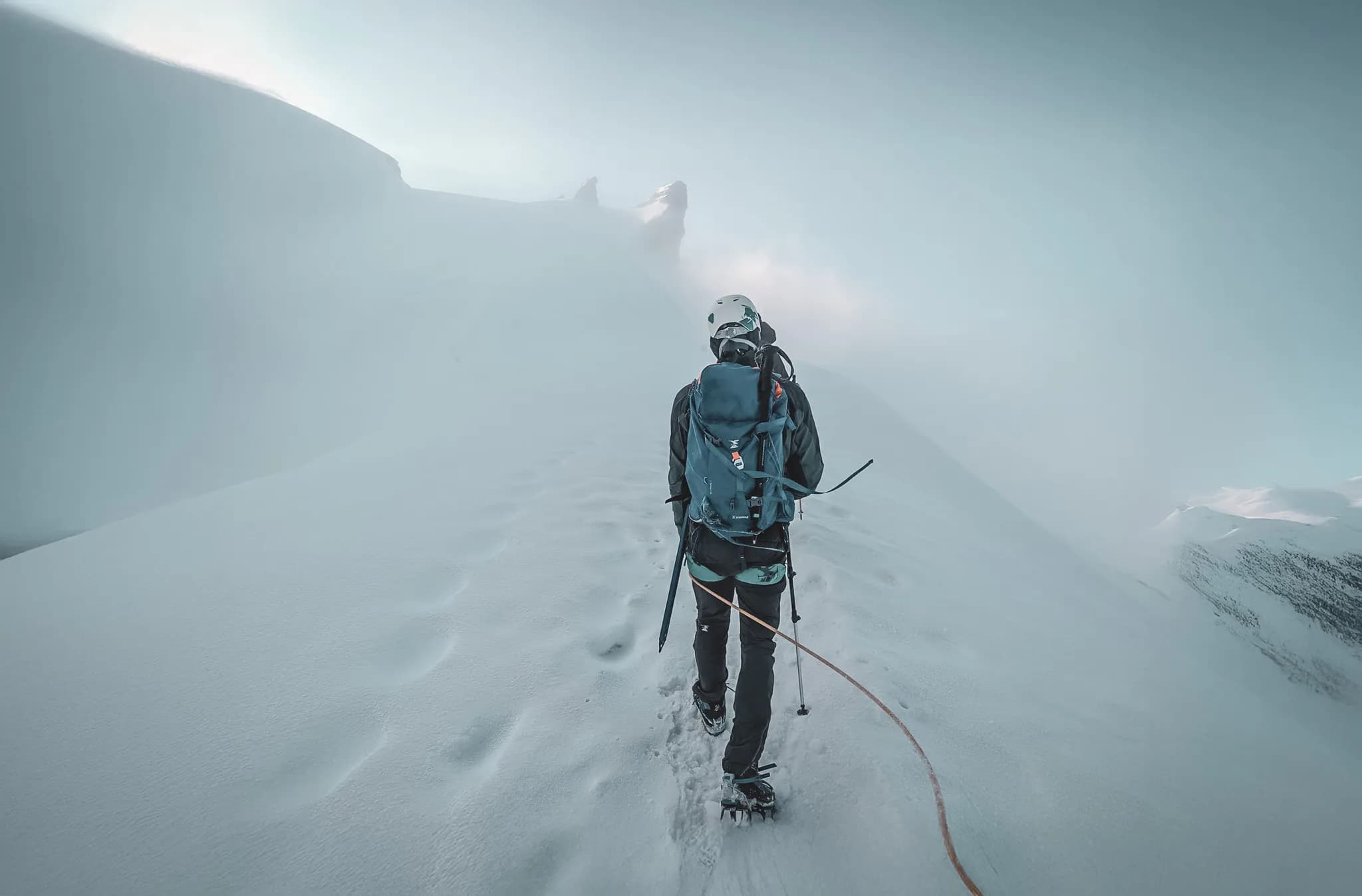 Een beginnende alpinist beklimt Gran Paradiso, gezekerd met een touw. Hij draagt geschikte uitrusting, inclusief een rugzak en stijgijzers, terwijl hij voorzichtig vooruitgaat op de besneeuwde helling.