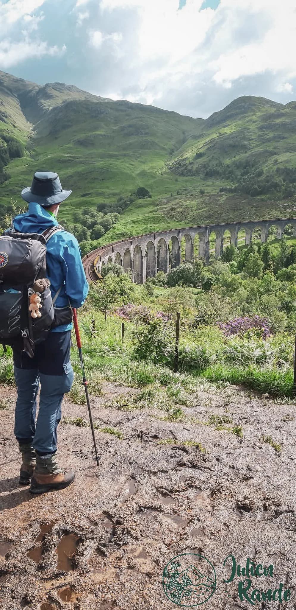 Wandelaar bewondert een majestueus viaduct in het hart van de Highlands, een groen en rustgevend landschap.