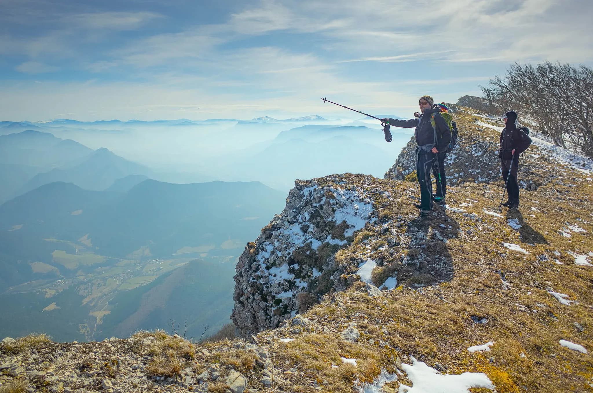 A group hiking on a Vercors summit, dazzled by a spectacular mountain panorama.