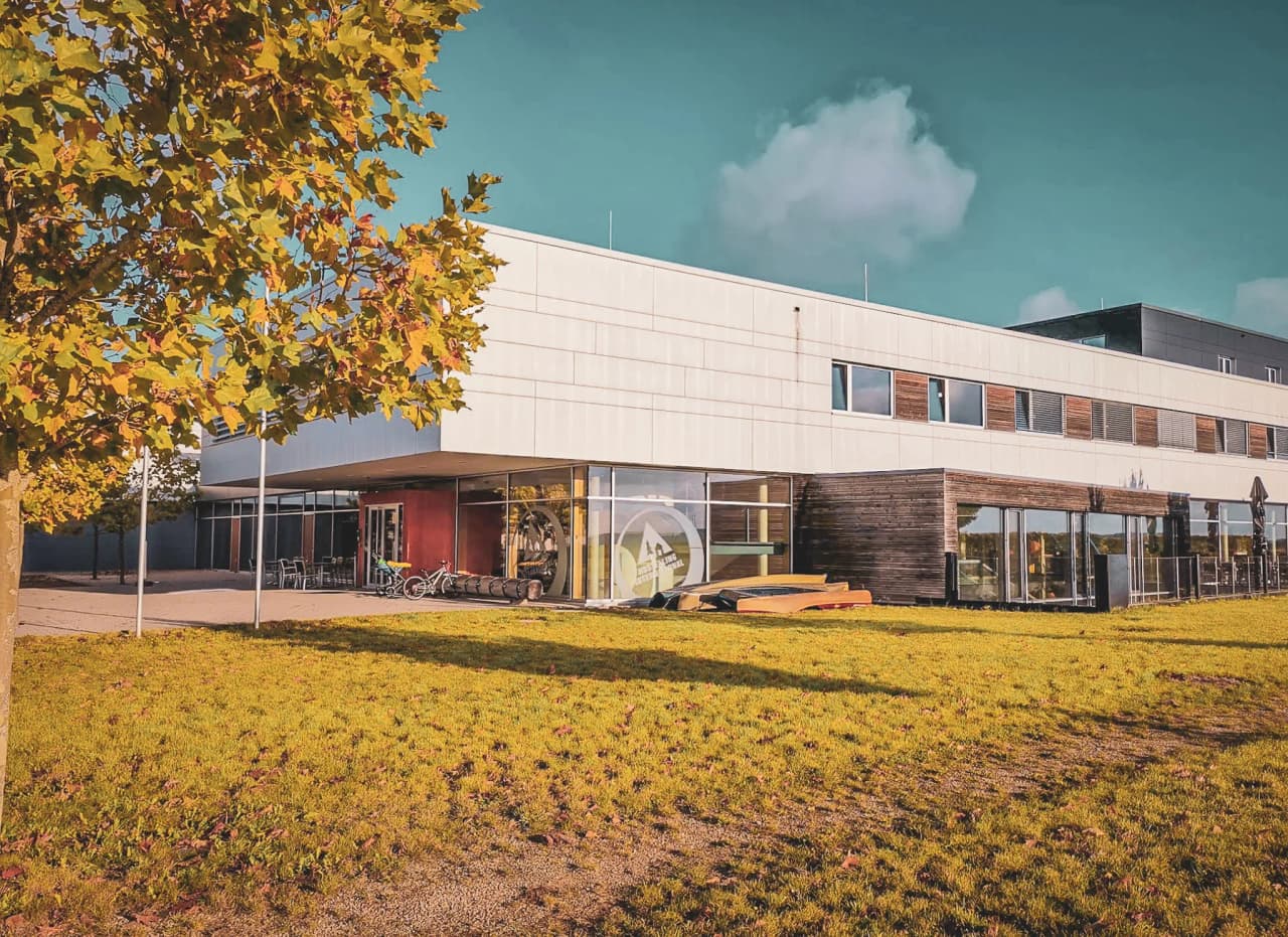 A modern building surrounded by greenery, promising adventures in the heart of the Mullerthal.