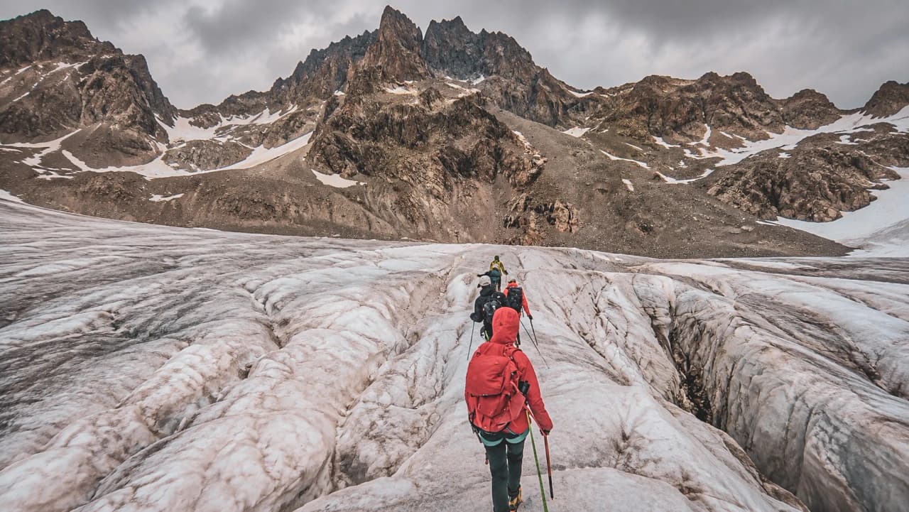Un groupe de randonneurs explore un glacier enchanteur sous des sommets majestueux dans les Écrins.