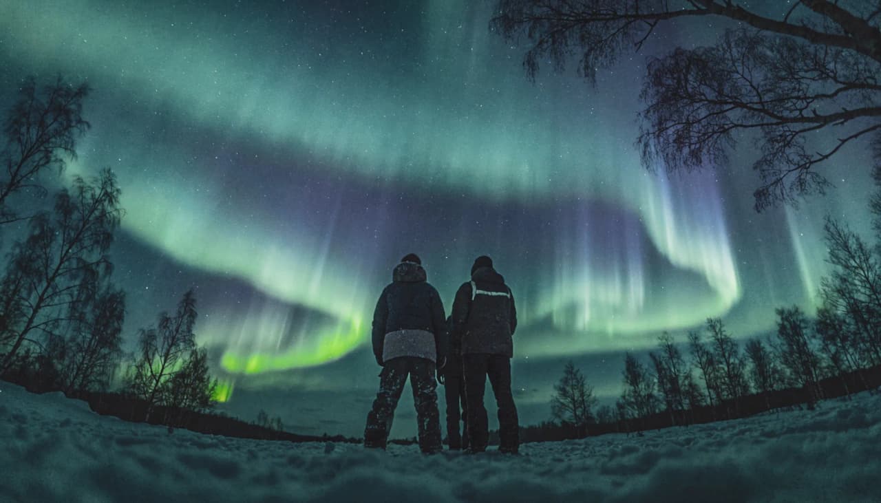 Twee avonturiers kijken naar het fonkelende noorderlicht in Noors Lapland.