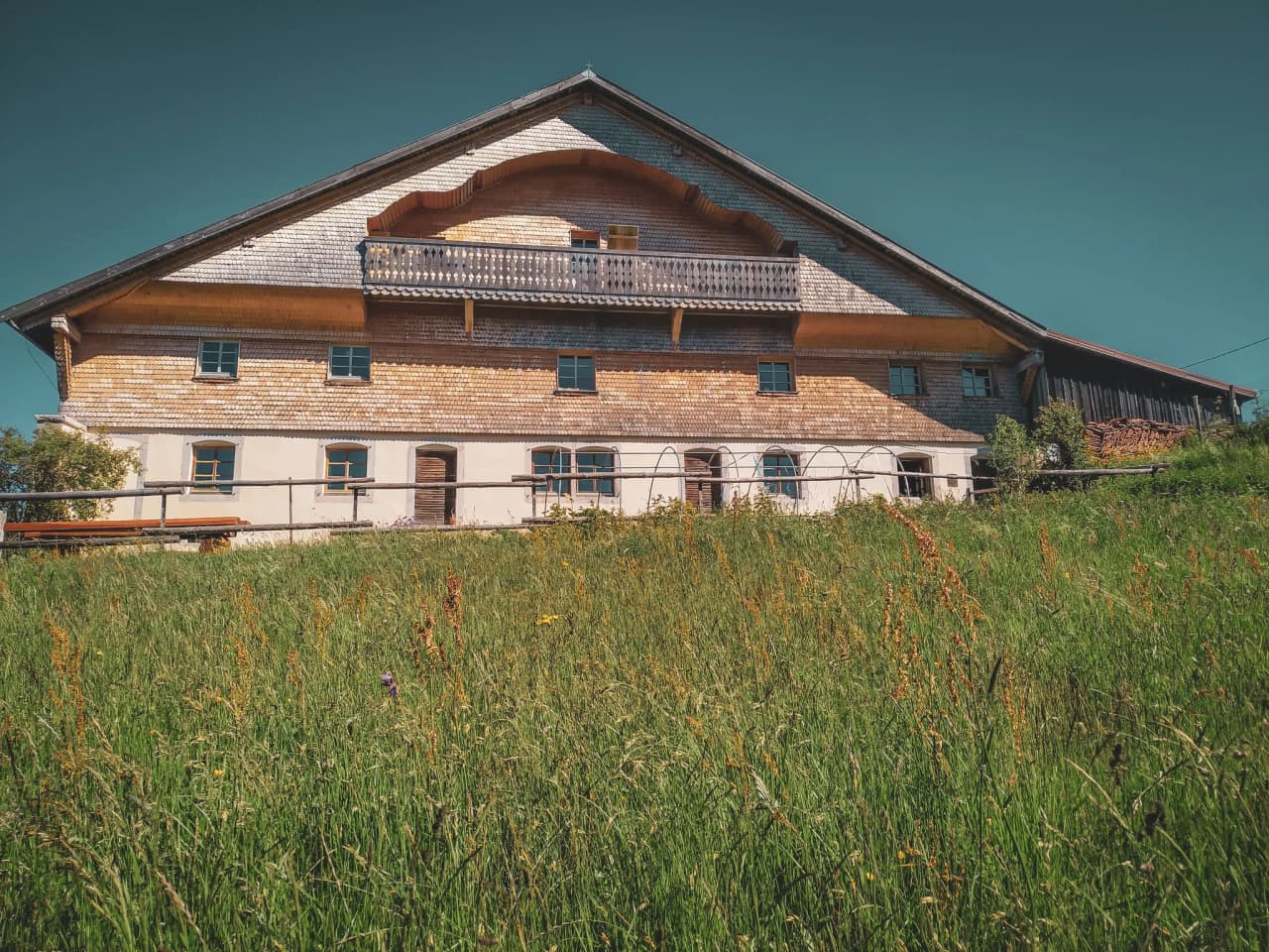 Een houten gebouw omringd door groene weiden, ideaal voor een vakantie in de Jura.