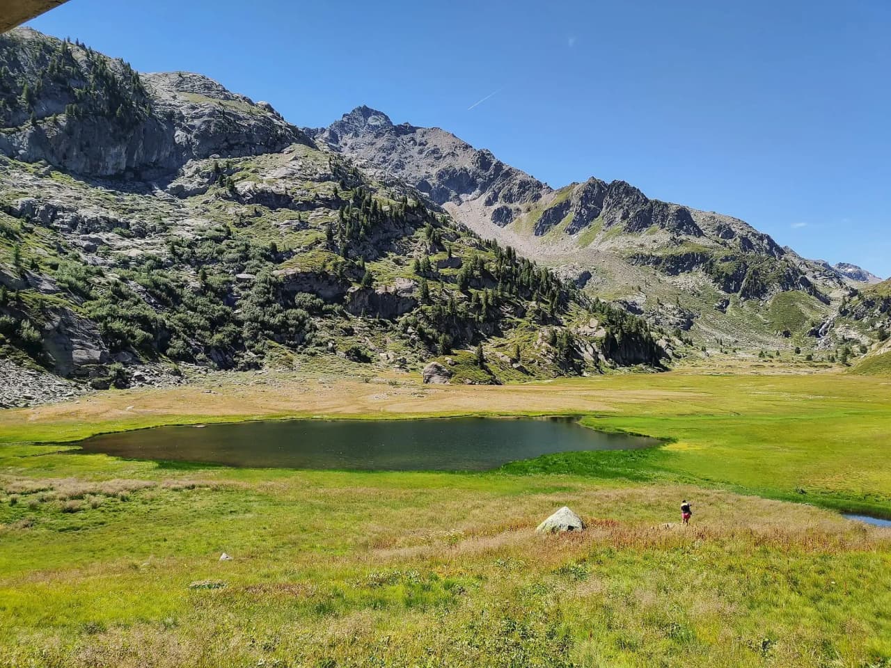 Un lac paisible entouré de montagnes verdoyantes, idéal pour une escapade alpine.