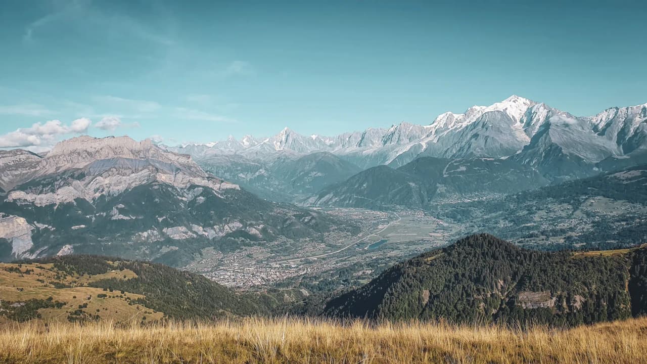 Adembenemend panoramisch uitzicht op het Aravis-gebergte, weelderig groene valleien en een stralend blauwe hemel.