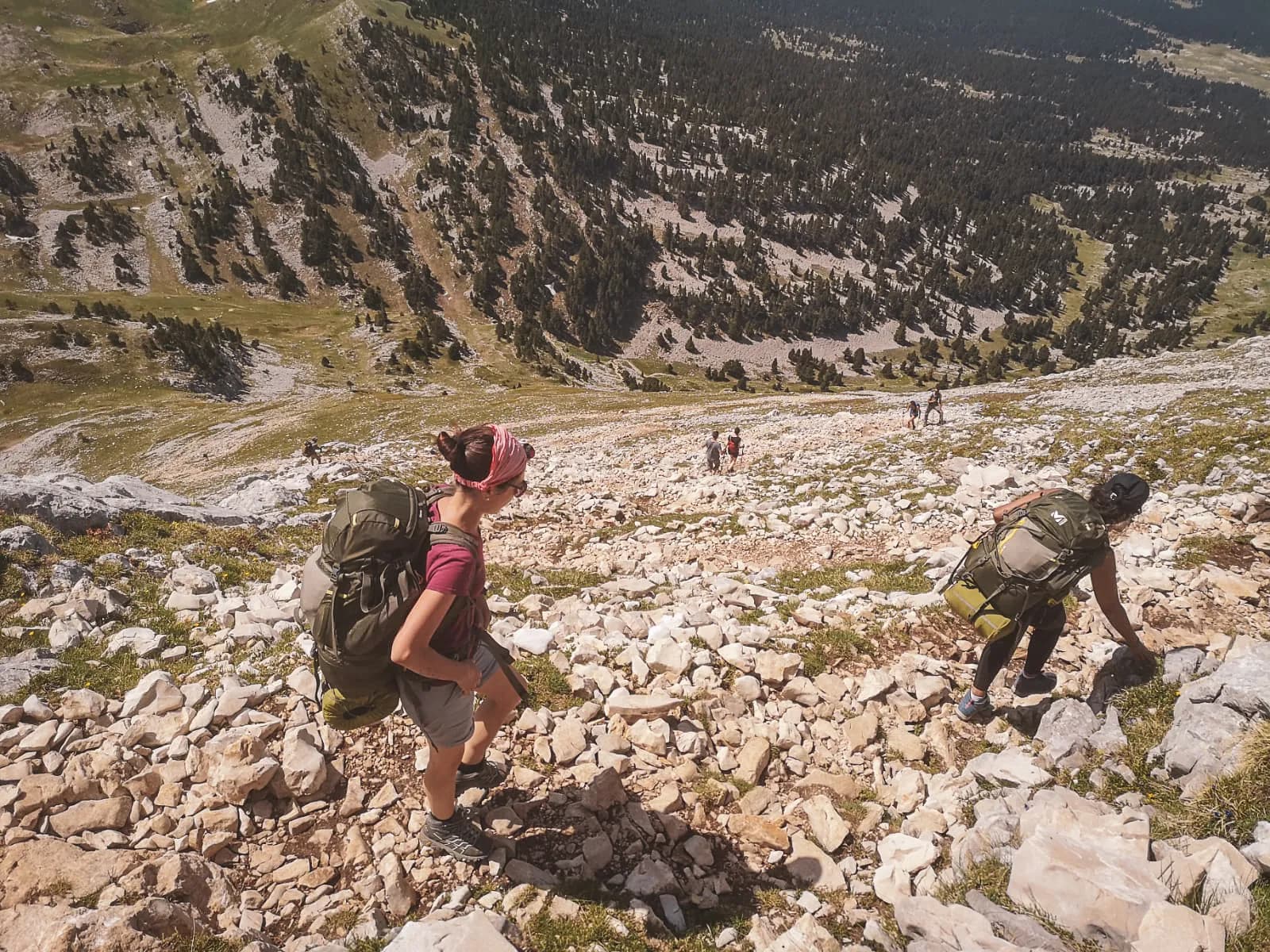 Een groep wandelaars beklimt rotsachtig terrein in het Vercors-massief en bewondert de natuur.