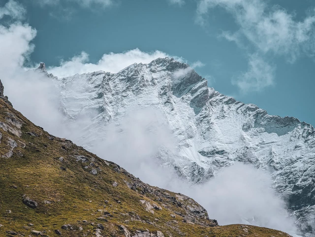 A majestic snow-capped peak rising from the clouds, an invitation to alpine adventure.