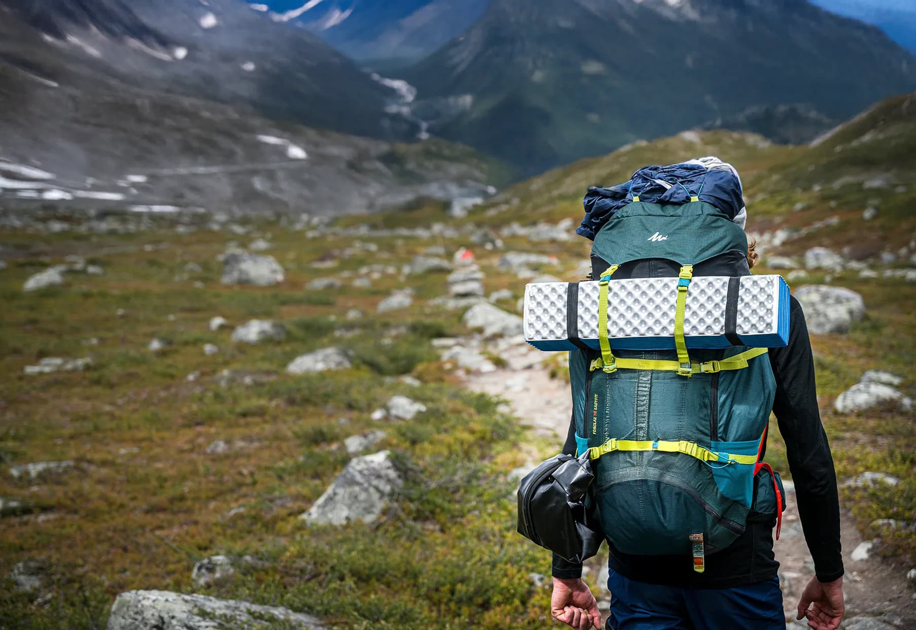 Mountain hiker with a big rucksack, surrounded by breathtaking Alpine scenery.