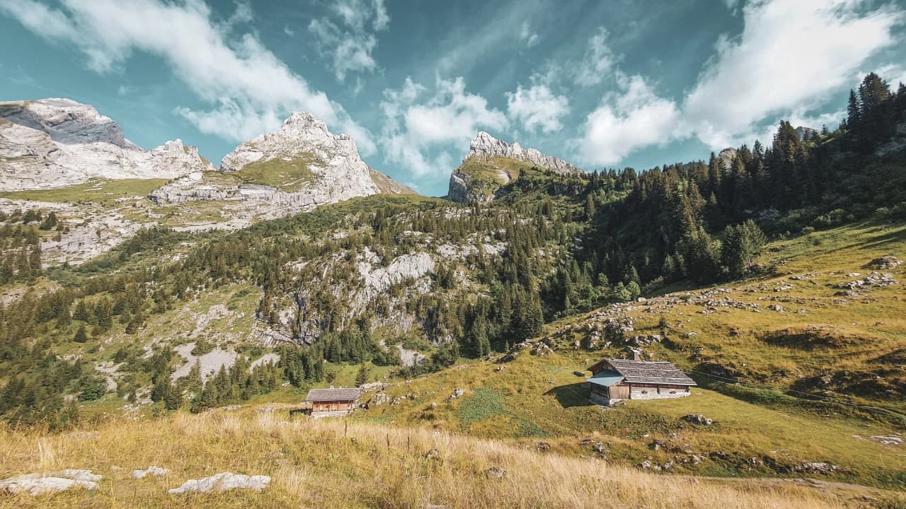 Een uitgestrekt alpenlandschap met majestueuze bergen en pittoreske chalets midden in de natuur.
