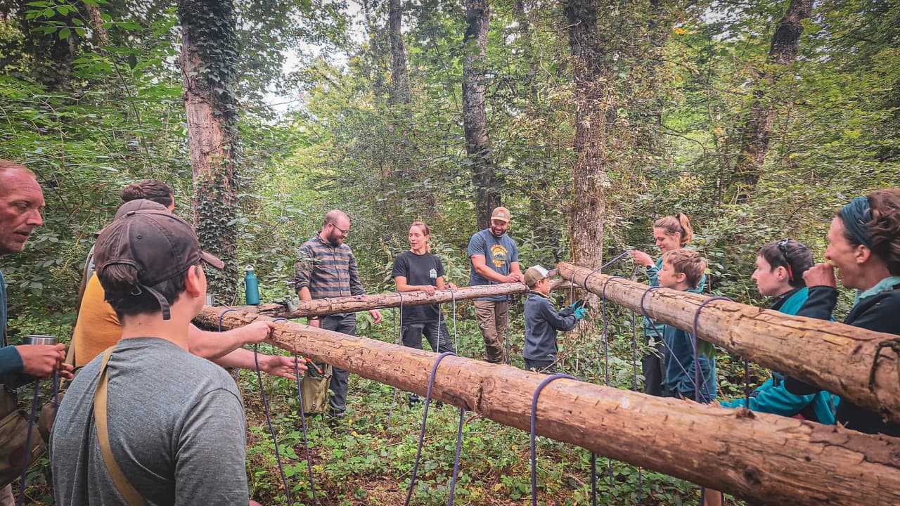 Un groupe apprend les techniques de survie en forêt, entouré de nature verdoyante.